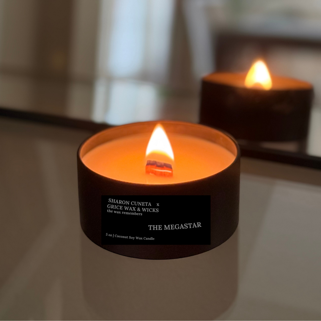 Two lit candles with visible labels on a reflective surface.