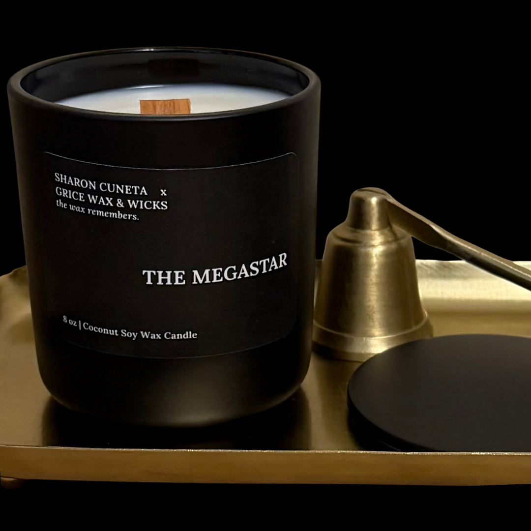 Black candle labeled 'The Megastar' on a gold tray with a black background