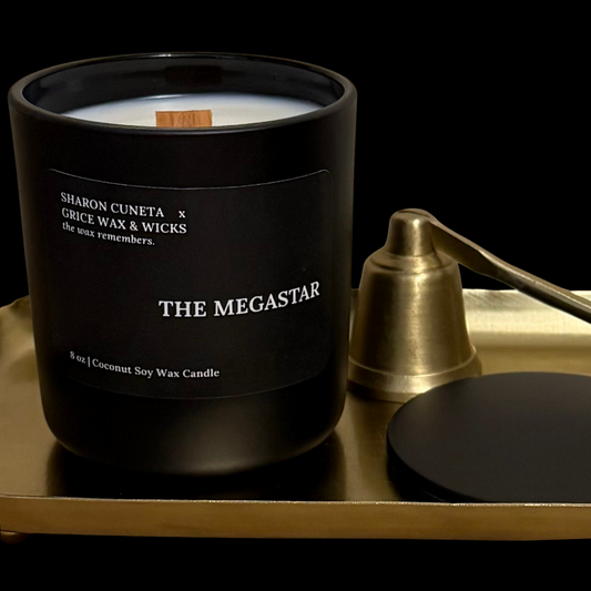 Black candle labeled 'The Megastar' on a gold tray with a black background