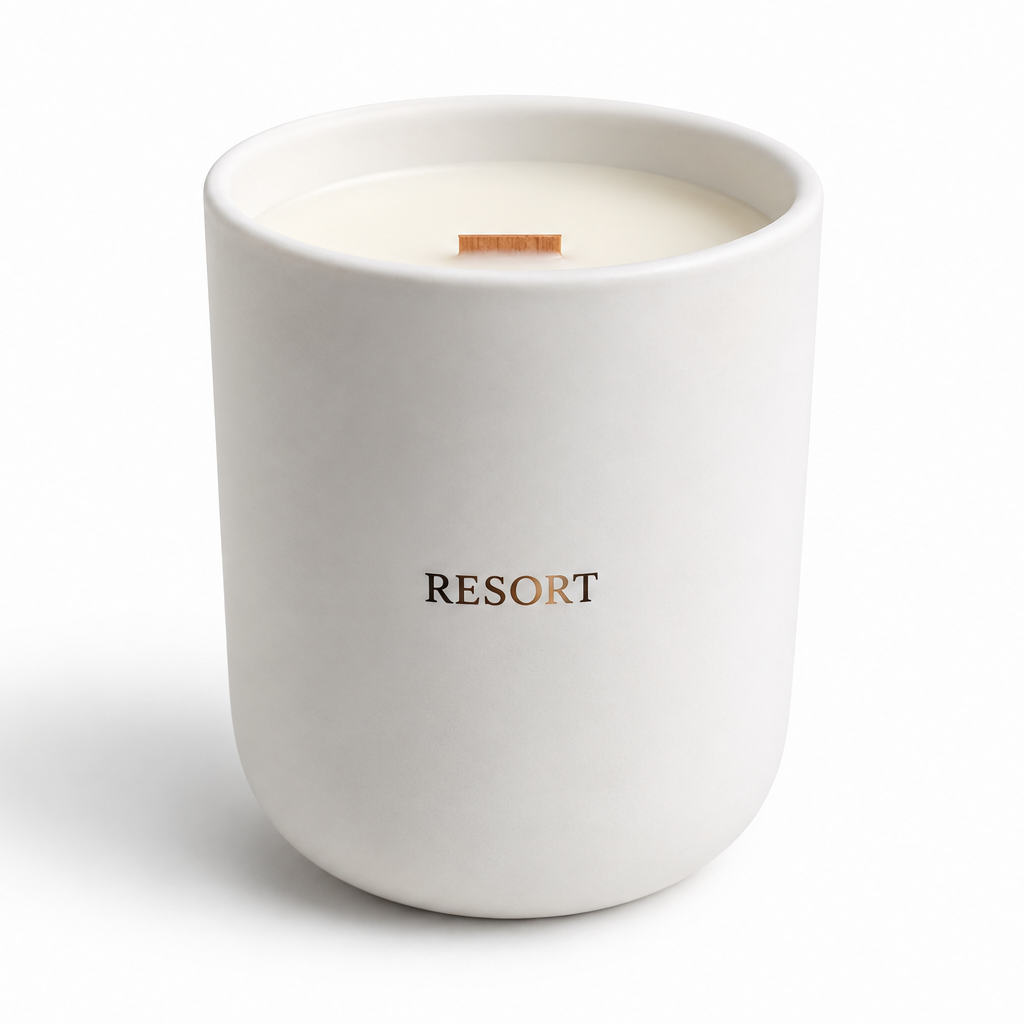 A white ceramic candle jar with the brand name 'RESORT' printed in black on the front, featuring a single wick and cream-colored wax, set against a plain white background.