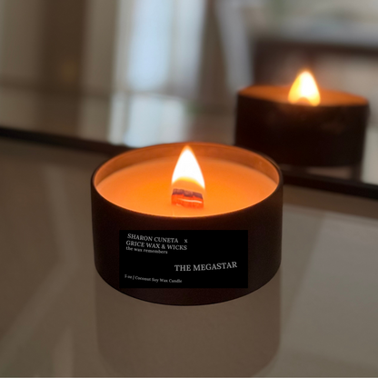 Two lit candles with visible labels on a reflective surface.