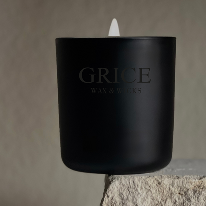 Black candle with 'Grice Wax & Works' branding on a stone surface.