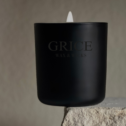 Black candle with 'Grice Wax & Works' branding on a stone surface.