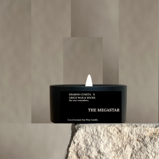 Black candle labeled 'The Megastar' by Sharon Cuneta x Grace Wax & Wicks on a textured surface.