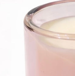 Close-up of a pink candle with a white wick against a white background
