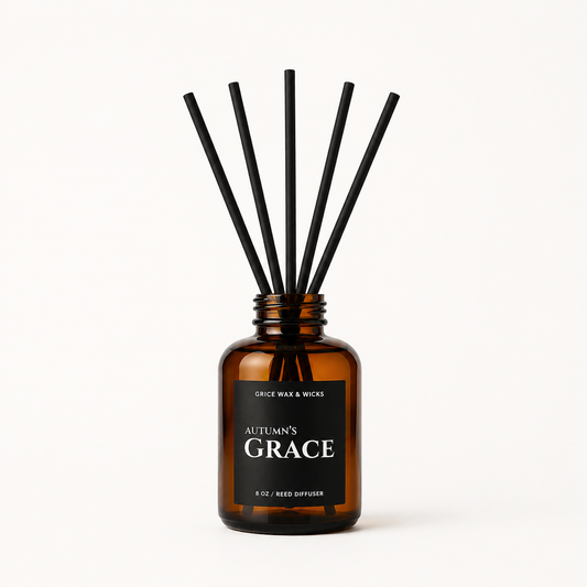Amber glass reed diffuser bottle with a black label reading 'Autumn's Grace' and six black reed sticks, photographed on a clean white background.