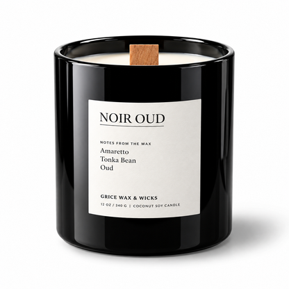 A black glass jar candle with a white label reading 'NOIR OUD' and a small wooden wick, photographed on a clean white background.