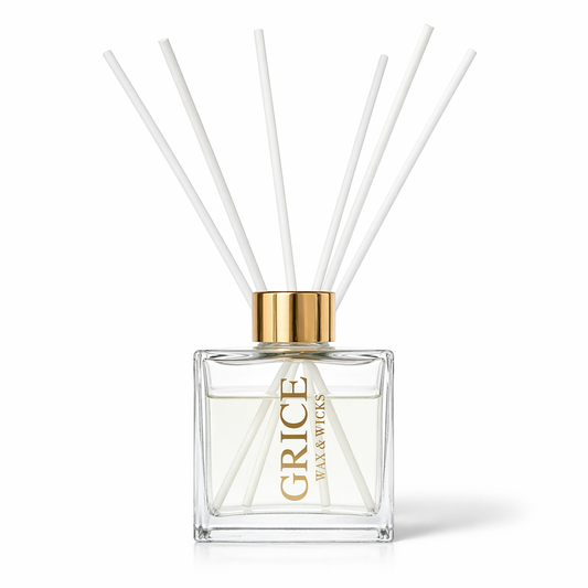 Clear diffuser bottle with white reeds and gold cap on a white background
