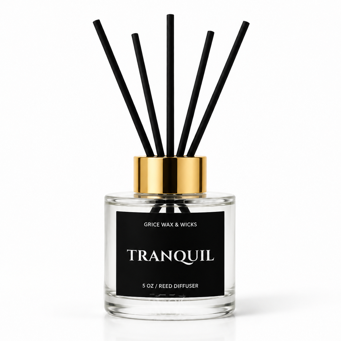A 5 oz reed diffuser bottle with a clear glass body, black label, and gold collar, featuring six black reed sticks, on a white background.