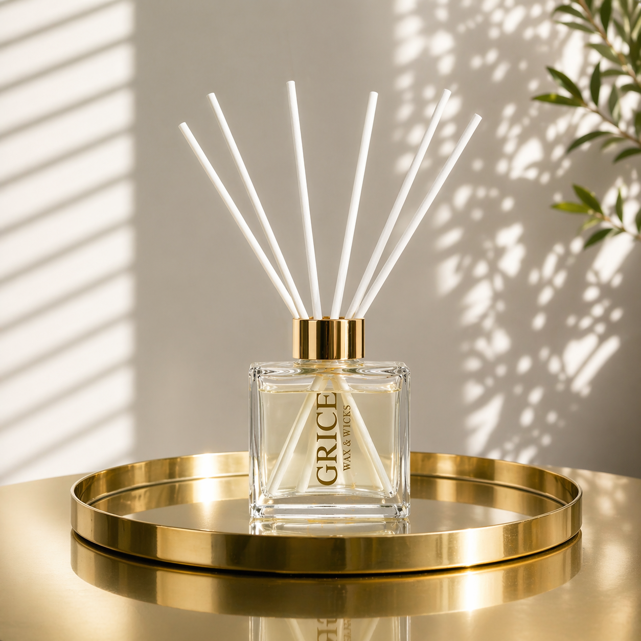 Reed diffuser with 'Grice' branding on a gold tray against a neutral wall.